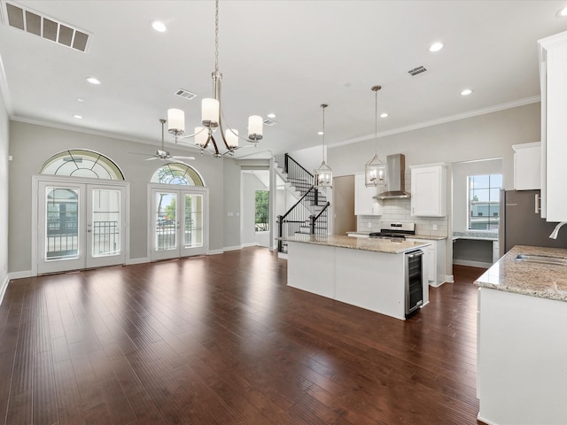 3303 Beverly Forest Dr, Houston, TX 77057 - kitchen with wall chimney range hood, a chandelier, stainless steel range with electric stovetop, beverage cooler, and open floor plan
