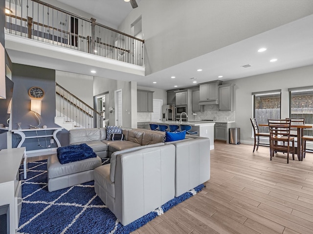 23027 Needlegrass Rd, Katy, TX 77493 - living room featuring a towering ceiling, light wood-style floors, stairway, and recessed lighting