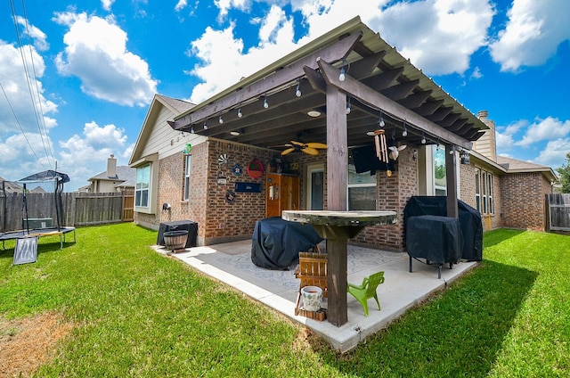 6215 Carnaby Ln, Rosenberg, TX 77471 - back of house featuring a trampoline, brick siding, a ceiling fan, and a fenced backyard