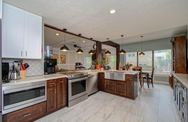 5422 Windy Lake Dr, Houston, TX 77345 - kitchen featuring stainless steel appliances, decorative backsplash, light stone countertops, decorative light fixtures, and white cabinetry