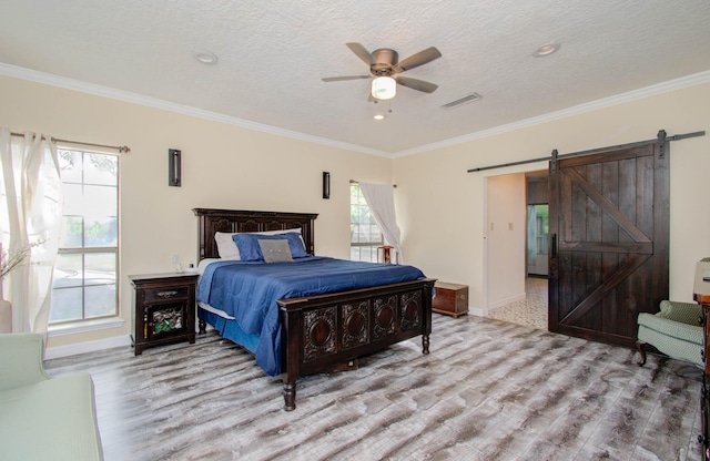 5422 Windy Lake Dr, Houston, TX 77345 - bedroom with a barn door, wood finished floors, crown molding, a ceiling fan, and a textured ceiling