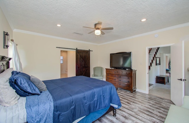 5422 Windy Lake Dr, Houston, TX 77345 - bedroom with a barn door, light wood-type flooring, ornamental molding, a textured ceiling, and a ceiling fan