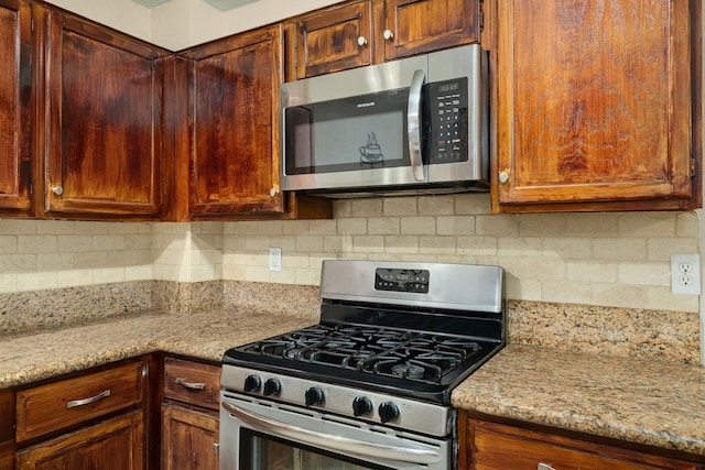 2351 Loyanne Dr, Spring, TX 77373 - kitchen with appliances with stainless steel finishes, decorative backsplash, and light stone countertops