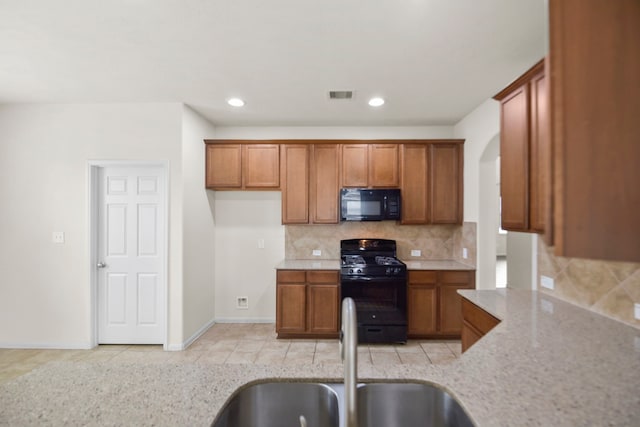 15107 Sequoia Meadow Ct, Humble, TX 77346 - kitchen with black appliances, brown cabinetry, backsplash, recessed lighting, and light stone counters
