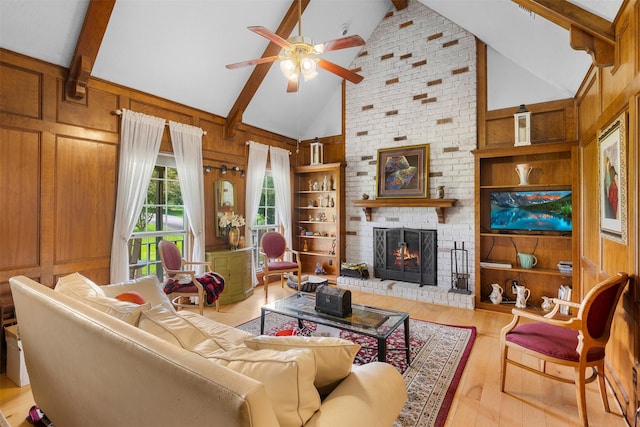 3357 Tamy Ln, Brenham, TX 77833 - living area featuring a ceiling fan, wood-type flooring, beam ceiling, a brick fireplace, and wood walls