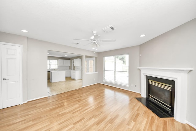 9410 Gatmere Ct, Sugar Land, TX 77498 - unfurnished living room with a glass covered fireplace, ceiling fan, healthy amount of natural light, light wood finished floors, and recessed lighting