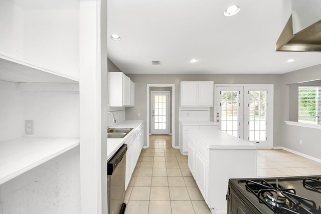 9410 Gatmere Ct, Sugar Land, TX 77498 - kitchen with stainless steel dishwasher, wall chimney range hood, light tile patterned floors, white cabinets, and light countertops