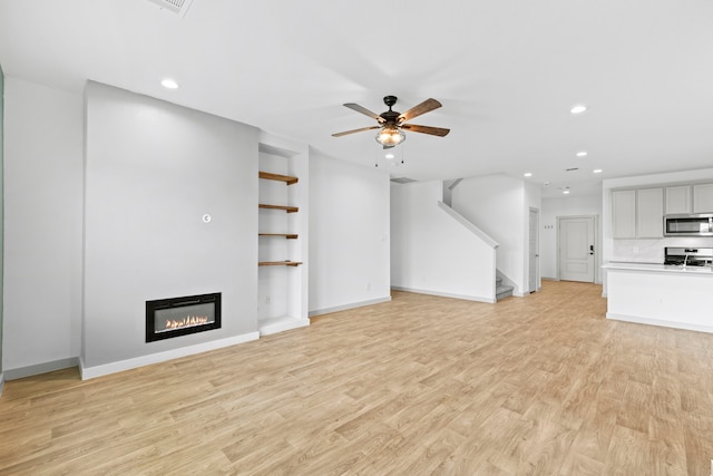 207 William Ln, Rosharon, TX 77583 - unfurnished living room with recessed lighting, a glass covered fireplace, a ceiling fan, stairs, and light wood-style floors
