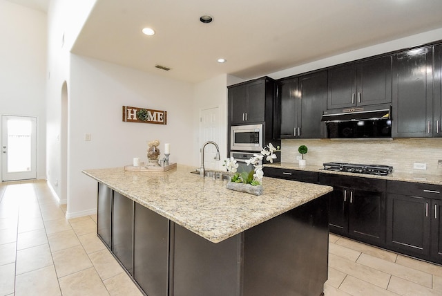 4615 Montcliff Bend Ln, Sugar Land, TX 77479 - kitchen with appliances with stainless steel finishes, dark cabinets, light tile patterned floors, tasteful backsplash, and recessed lighting