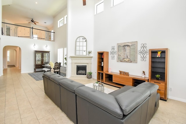 4615 Montcliff Bend Ln, Sugar Land, TX 77479 - living room with a ceiling fan, a high ceiling, arched walkways, light tile patterned floors, and a fireplace with raised hearth