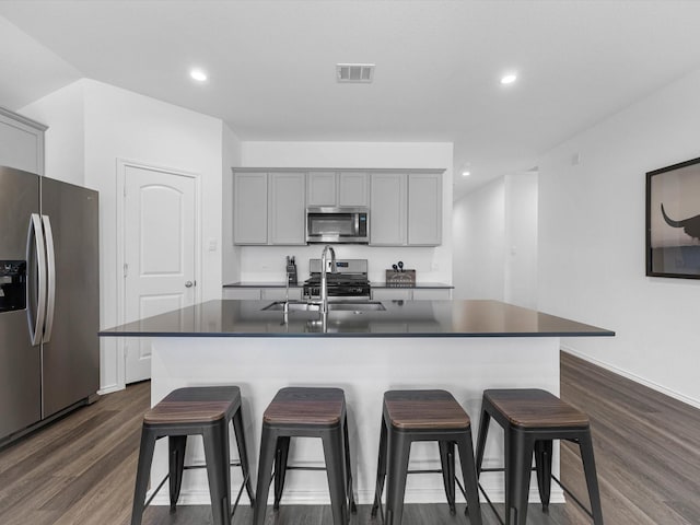 17831 Sommerset Falls Ln, Crosby, TX 77532 - kitchen with appliances with stainless steel finishes, gray cabinetry, dark countertops, a breakfast bar area, and recessed lighting