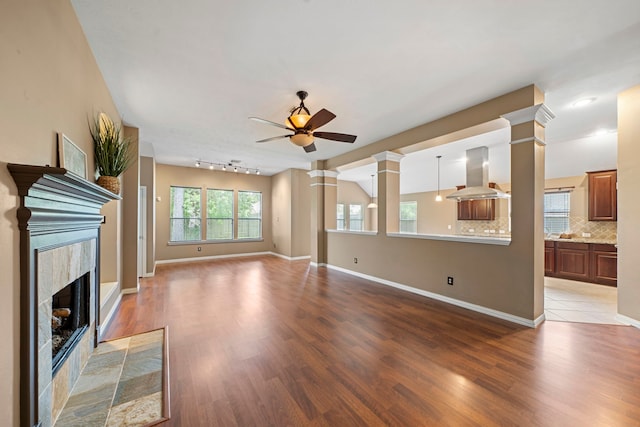 15015 Cozy Hollow Ln, Houston, TX 77044 - unfurnished living room featuring decorative columns, light wood finished floors, a ceiling fan, and a high end fireplace