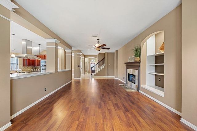 15015 Cozy Hollow Ln, Houston, TX 77044 - unfurnished living room featuring wood finished floors, a tiled fireplace, ceiling fan, and stairs