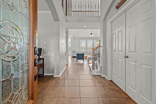 14402 Hazeldale Dr, Cypress, TX 77429 - tiled entryway featuring ornamental molding, a ceiling fan, arched walkways, and stairs