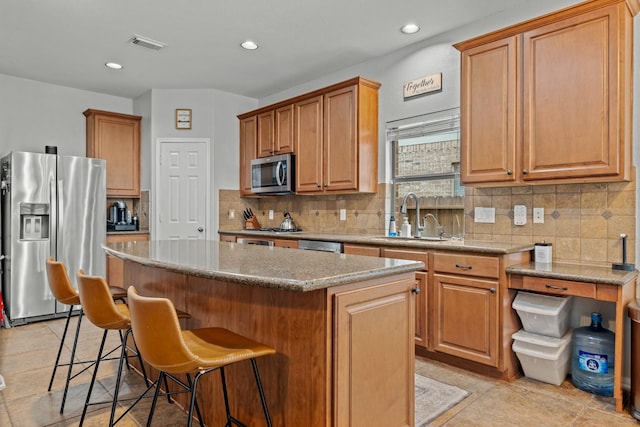 14402 Hazeldale Dr, Cypress, TX 77429 - kitchen with appliances with stainless steel finishes, a kitchen island, a kitchen breakfast bar, tasteful backsplash, and light stone counters