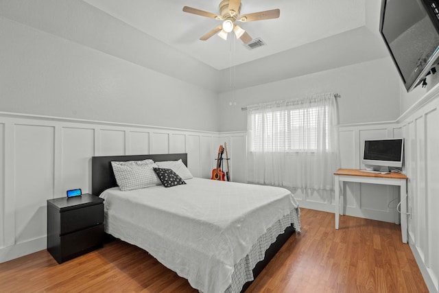 14402 Hazeldale Dr, Cypress, TX 77429 - bedroom with a decorative wall, light wood-style floors, wainscoting, and ceiling fan