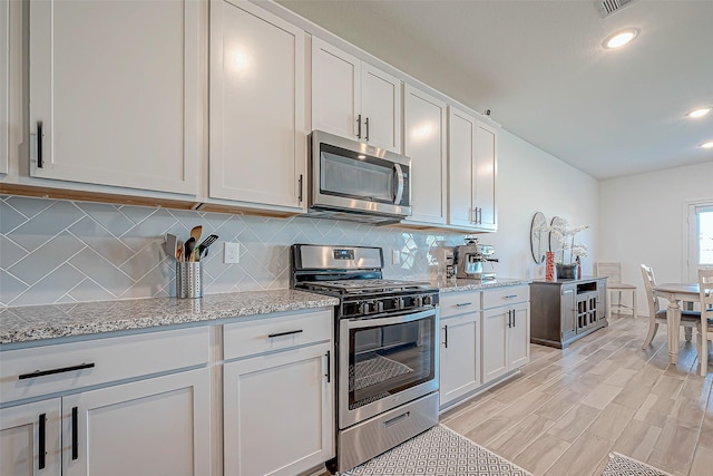 5703 Morning Vista Rd, Katy, TX 77493 - kitchen featuring appliances with stainless steel finishes, tasteful backsplash, white cabinetry, recessed lighting, and light stone countertops