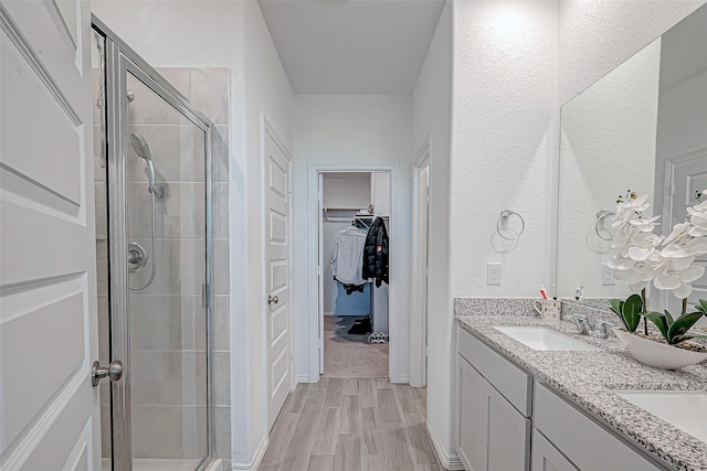 5703 Morning Vista Rd, Katy, TX 77493 - bathroom featuring a stall shower, double vanity, a walk in closet, and wood finished floors