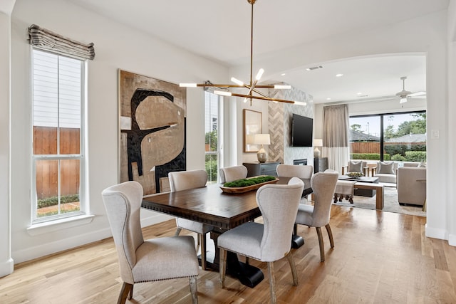 919 Worthshire St, Houston, TX 77008 - dining room featuring light wood-style floors, a fireplace, a chandelier, arched walkways, and recessed lighting