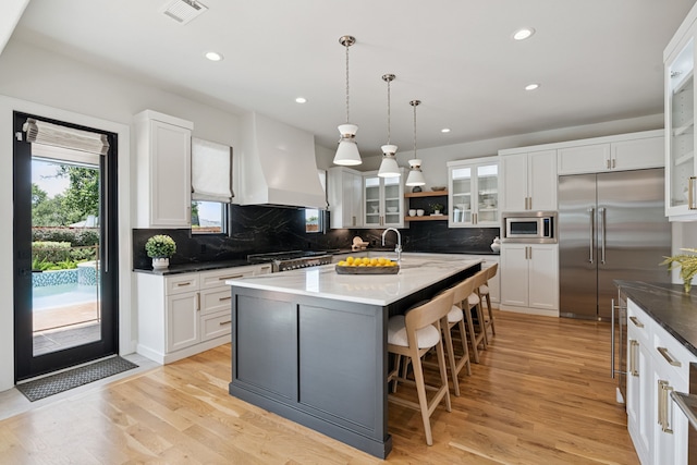 919 Worthshire St, Houston, TX 77008 - kitchen featuring built in appliances, wall chimney range hood, recessed lighting, backsplash, and white cabinetry