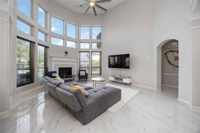 4306 Dalea Clover Ln, Manvel, TX 77578 - living area with marble tiled floors, ceiling fan, a premium fireplace, a towering ceiling, and arched walkways