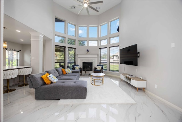 4306 Dalea Clover Ln, Manvel, TX 77578 - living area featuring a fireplace, a ceiling fan, marble tiled floors, ornate columns, and a towering ceiling
