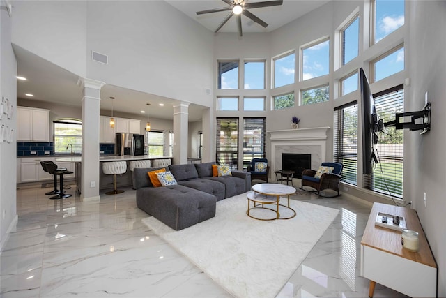 4306 Dalea Clover Ln, Manvel, TX 77578 - living room with ornate columns, light marble finish flooring, a ceiling fan, a premium fireplace, and a high ceiling