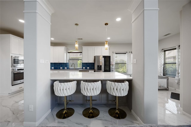 4306 Dalea Clover Ln, Manvel, TX 77578 - kitchen with stainless steel appliances, light marble finish floors, backsplash, a kitchen bar, and healthy amount of natural light