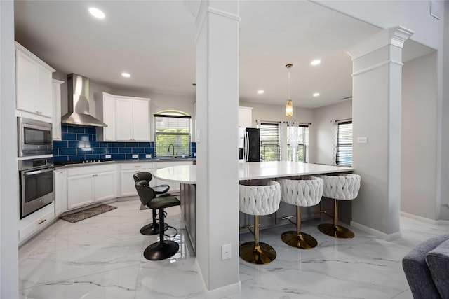 4306 Dalea Clover Ln, Manvel, TX 77578 - kitchen with wall chimney range hood, appliances with stainless steel finishes, light marble finish flooring, recessed lighting, and a breakfast bar area