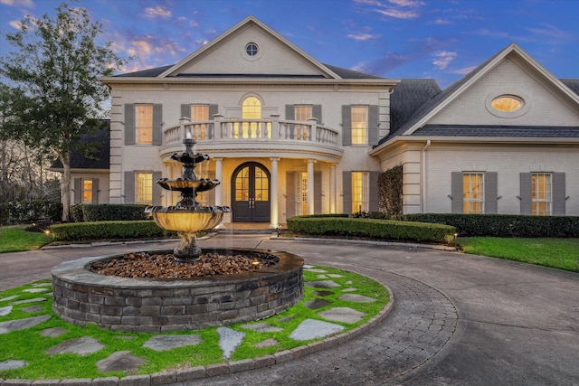 106 Melody Ln, Friendswood, TX 77546 - view of front facade featuring a balcony, french doors, brick siding, and curved driveway