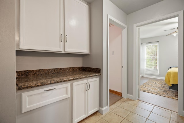 4018 Shady Springs Dr, Seabrook, TX 77586 - kitchen with white cabinets, light tile patterned floors, ceiling fan, and dark stone countertops