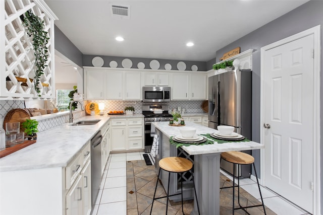 4311 Pebble Beach Dr, League City, TX 77573 - kitchen with stainless steel appliances, a breakfast bar, light tile patterned floors, decorative backsplash, and white cabinets