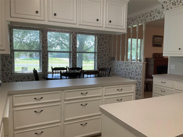 30 Piper Ln, Normangee, TX 77871 - kitchen with wallpapered walls, light countertops, crown molding, white cabinetry, and plenty of natural light