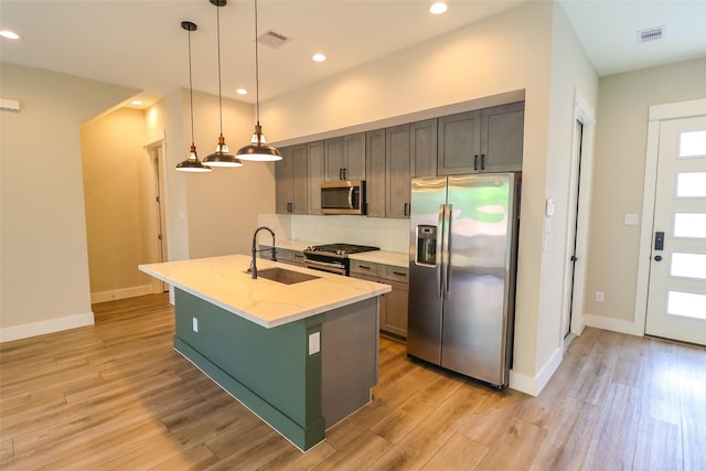 5213 Pinemont Creek Ln, Houston, TX 77018 - kitchen featuring stainless steel appliances, light wood finished floors, light stone counters, a center island with sink, and pendant lighting