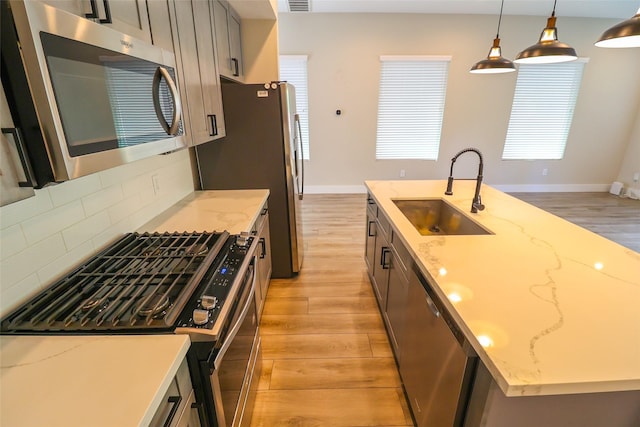 5213 Pinemont Creek Ln, Houston, TX 77018 - kitchen featuring stainless steel appliances, light wood finished floors, tasteful backsplash, decorative light fixtures, and light stone countertops