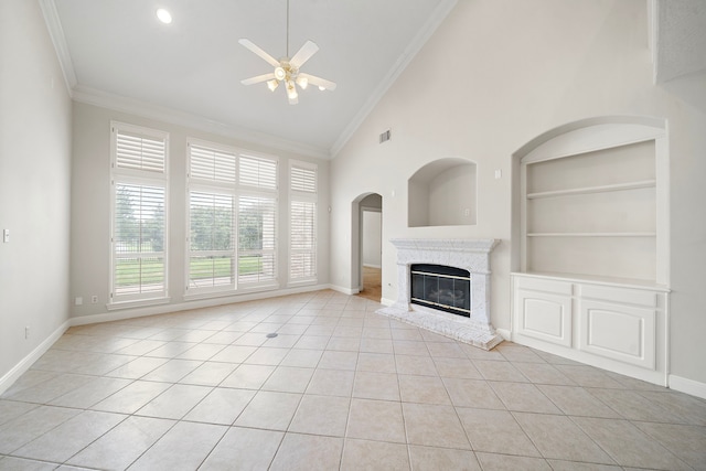 16426 Torry View Ter, Houston, TX 77095 - unfurnished living room featuring a ceiling fan, built in features, light tile patterned floors, a glass covered fireplace, and crown molding