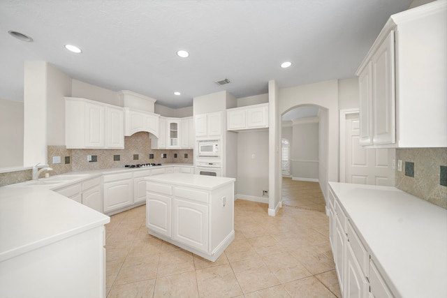 16426 Torry View Ter, Houston, TX 77095 - kitchen with white appliances, arched walkways, light tile patterned flooring, decorative backsplash, and white cabinets