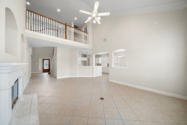 16426 Torry View Ter, Houston, TX 77095 - unfurnished living room with a ceiling fan, light tile patterned flooring, a high ceiling, ornamental molding, and a glass covered fireplace