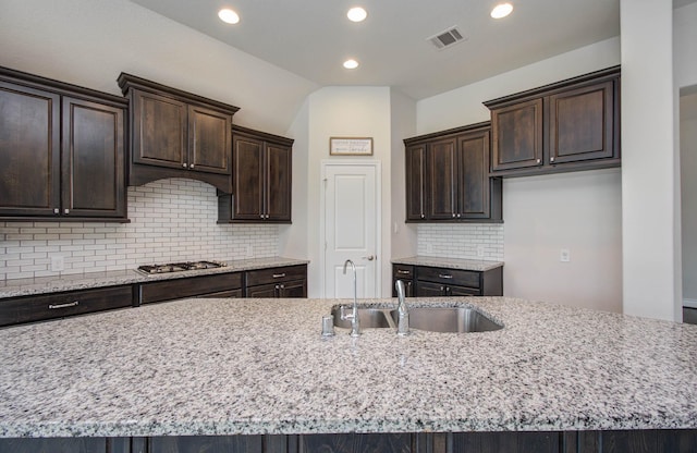 3605 Dolan Trail Ct, Pearland, TX 77584 - kitchen with recessed lighting, tasteful backsplash, dark brown cabinets, light stone countertops, and stainless steel gas stovetop