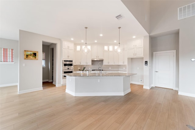 14315 Summer Prairie Trl, Cypress, TX 77433 - kitchen featuring white cabinets, light wood-style floors, tasteful backsplash, double oven, and recessed lighting