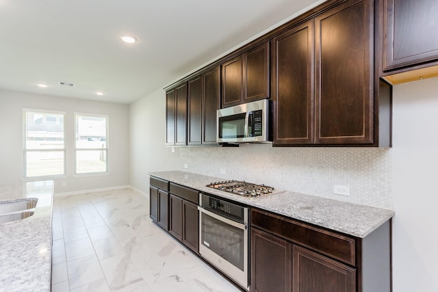 8506 Belfast Manor Ln, Richmond, TX 77407 - kitchen with appliances with stainless steel finishes, light marble finish flooring, dark brown cabinetry, recessed lighting, and backsplash