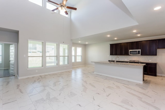8506 Belfast Manor Ln, Richmond, TX 77407 - kitchen with stainless steel microwave, open floor plan, a ceiling fan, recessed lighting, and backsplash