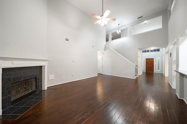 8014 Sports Haven Dr, Humble, TX 77346 - unfurnished living room featuring a high ceiling, a tiled fireplace, ceiling fan, hardwood / wood-style flooring, and stairway
