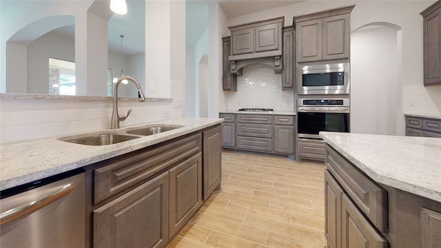 225 Sycamore, Lumberton, TX 77657 - kitchen featuring appliances with stainless steel finishes, arched walkways, decorative backsplash, and light stone counters