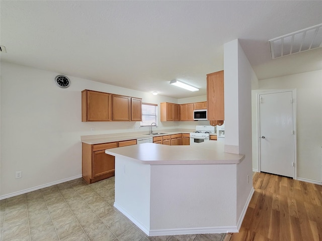 18403 Fair Grange Ln, Cypress, TX 77433 - kitchen with white appliances, light countertops, a peninsula, and brown cabinetry