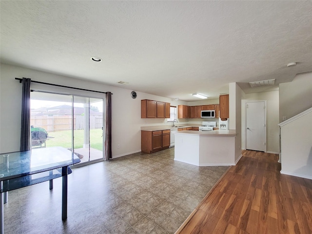 18403 Fair Grange Ln, Cypress, TX 77433 - kitchen featuring white appliances, brown cabinetry, light countertops, a textured ceiling, and a peninsula