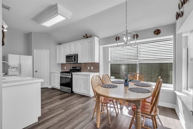 3731 Crescent Dr, Pearland, TX 77584 - kitchen with stainless steel appliances, backsplash, dark wood-type flooring, white cabinetry, and vaulted ceiling