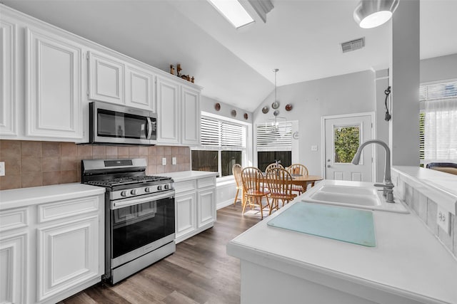 3731 Crescent Dr, Pearland, TX 77584 - kitchen featuring appliances with stainless steel finishes, vaulted ceiling, white cabinets, decorative backsplash, and dark wood-type flooring