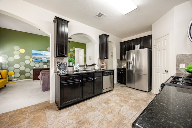 15110 Sierra Ridge Dr, Humble, TX 77396 - kitchen with appliances with stainless steel finishes, arched walkways, light stone finish flooring, dark stone counters, and decorative backsplash