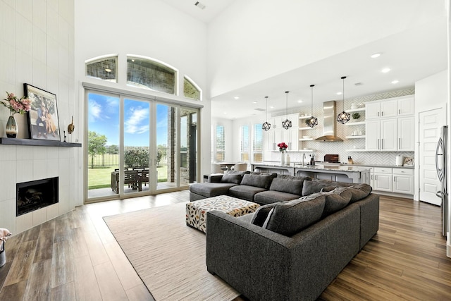 2607 Open Prairie Ln, Katy, TX 77493 - living area with a high ceiling, dark wood-style flooring, a tiled fireplace, and recessed lighting